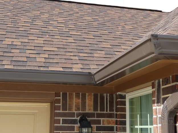 brown metal gutters wrapping around a brick home