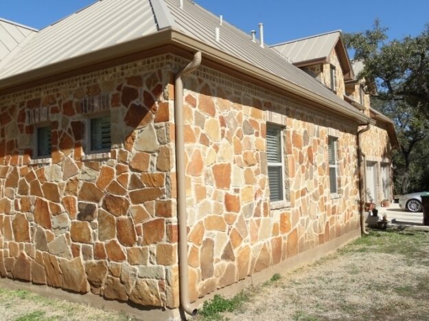 stone home with brown gutters and downspouts