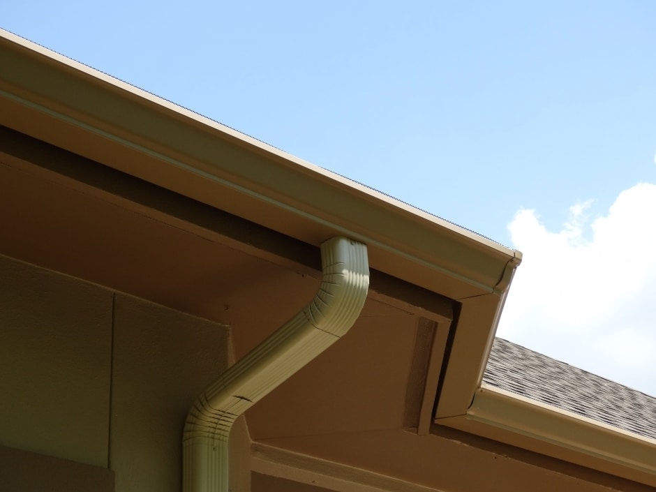 beige downspout and rain gutters with angled joinings