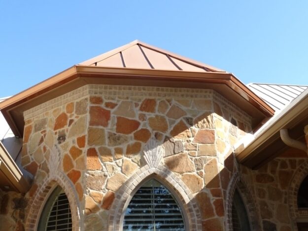 metal roof on stone home with copper rain gutters