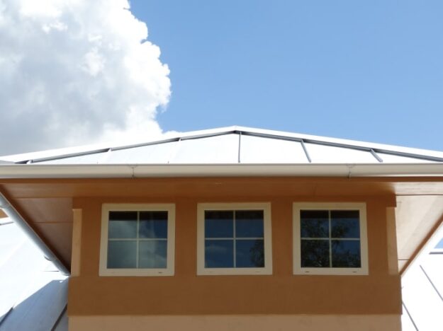 three windows with metal rain gutters and a metal roof