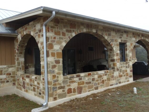 stone porch with metal rain gutters and downspout