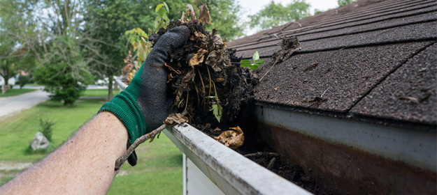 featured-image-how-to-prepare-gutters-for-winter man taking leaves and soil out of gutters