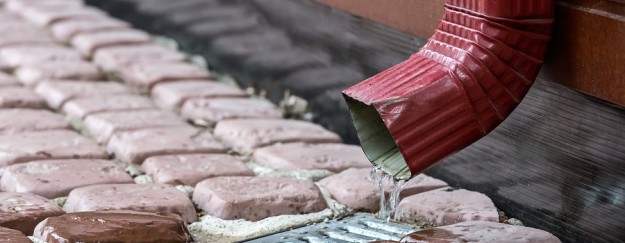 Red Downspout Rain water runs out of a downspout from the gutter