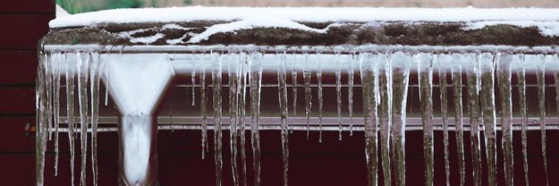 gutters with icicles next to a snowy roof