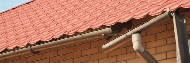Broken rain gutter hanging from a red shingle roof on a brick home
