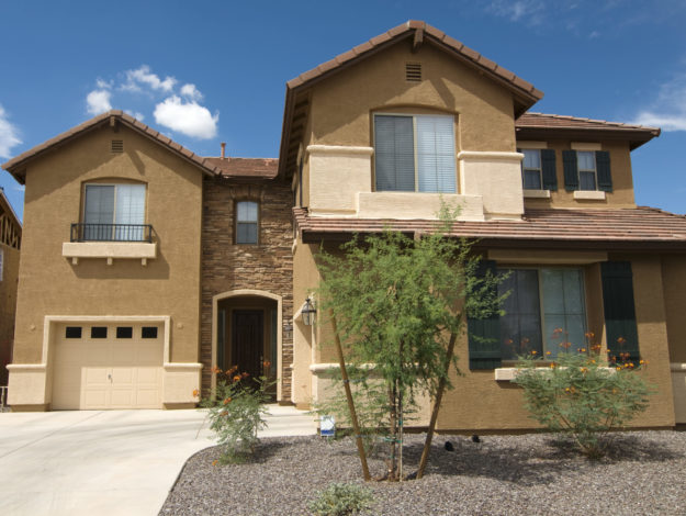 Large brown home with red tile roof and brown gutters