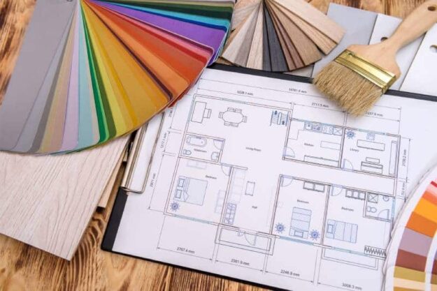 What to Expect When You Have Your House Painted Home floor plan, paint samples, and paint brushes fanned out on a hardwood floor depict the design plan for house painting.